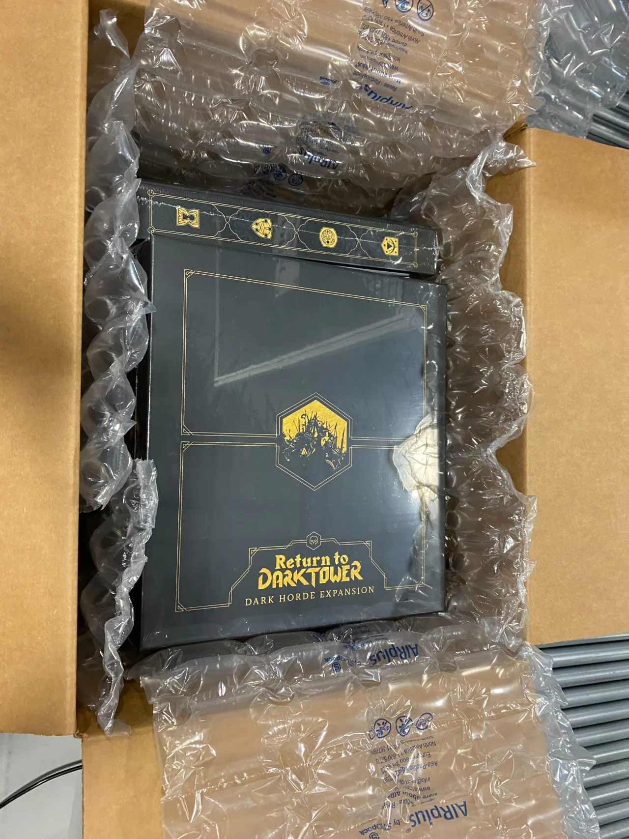 A board game box packed in bubble wrap inside a shipping carton